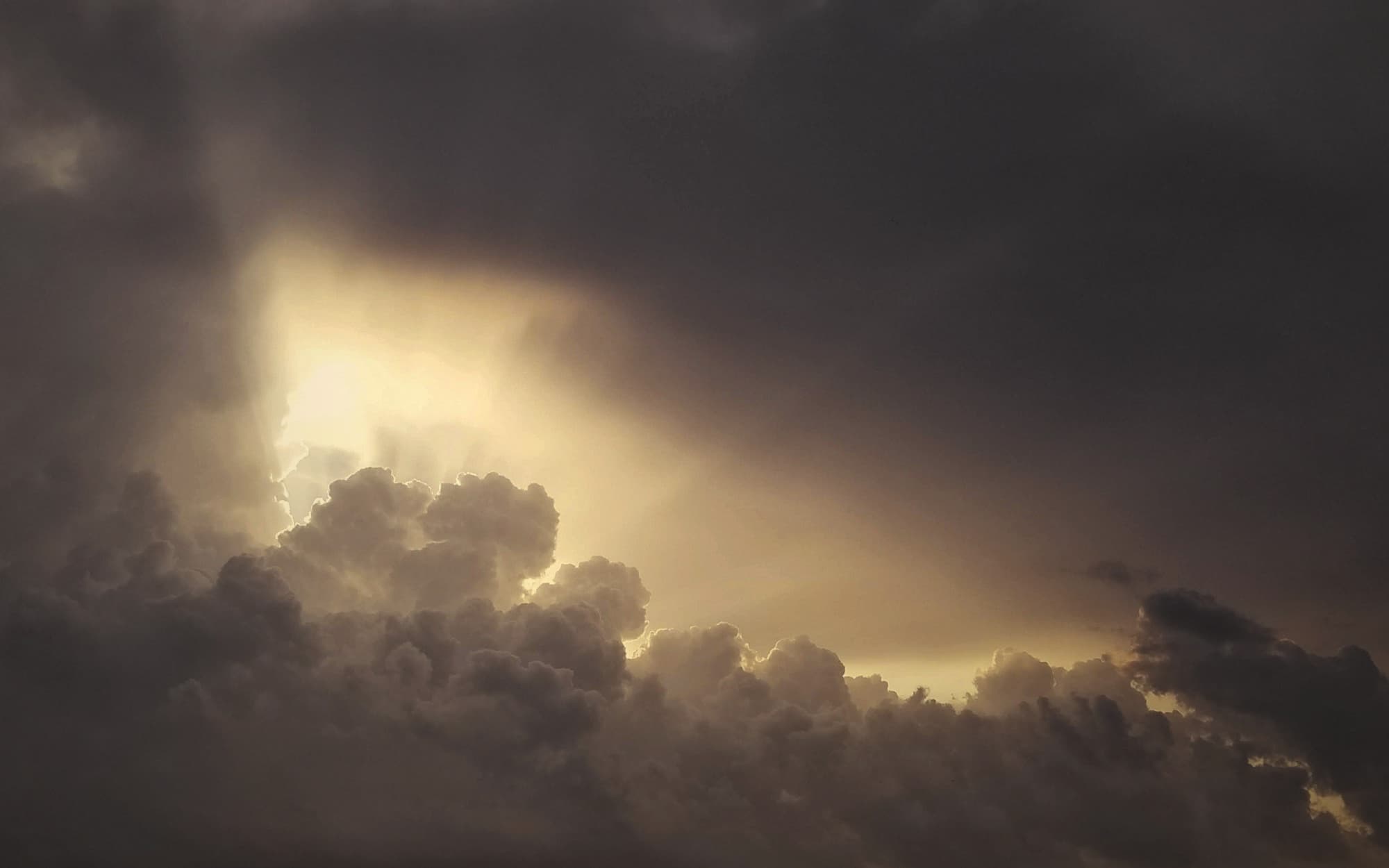 The sun glowing through a break in dark, heavy clouds
